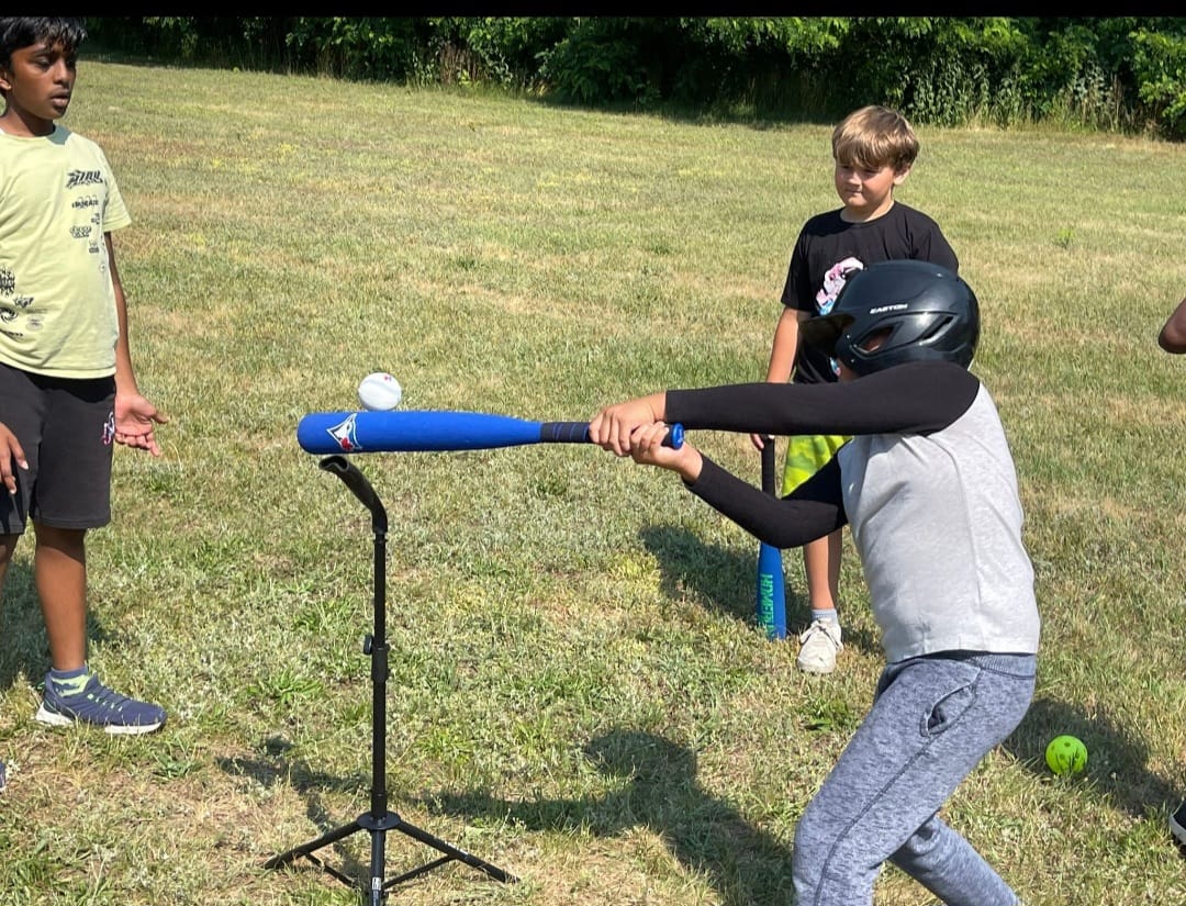 Youth baseball batter driving the ball off the tee in Toronto
