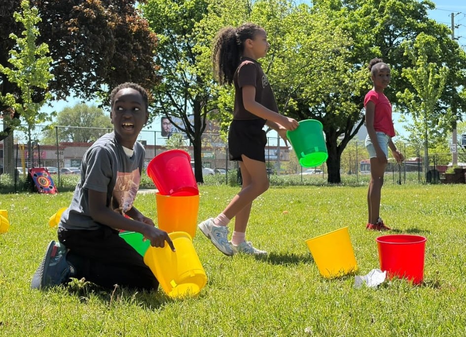 Children playing colorful bucket games on the grass field