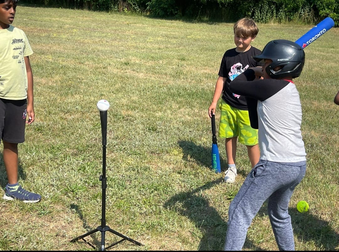 Youth batter with safety helmet taking aim at baseball tee
